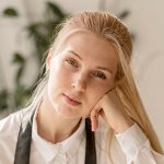 Junge blonde Frau in weißem Hemd blickt ruhig in die Kamera