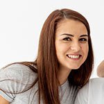 Lächelnde Frau mit braunen Haaren, trägt ein graues T-Shirt.