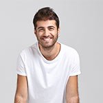 Lächelnder junger Mann in einem weißen T-Shirt, sitzt entspannt.