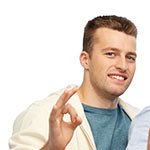Junger Mann in einem weißen Hoodie, macht mit seiner Hand das 'OK'-Zeichen und lächelt.
